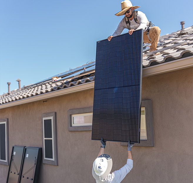 a solar pros worker lifting a solar panel to give his co worker for installation