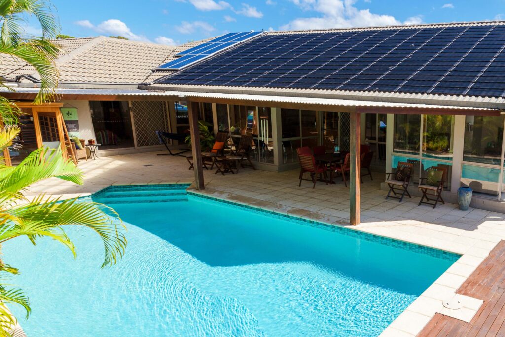 Relaxing poolside at a sunny home with solar panels on the roof