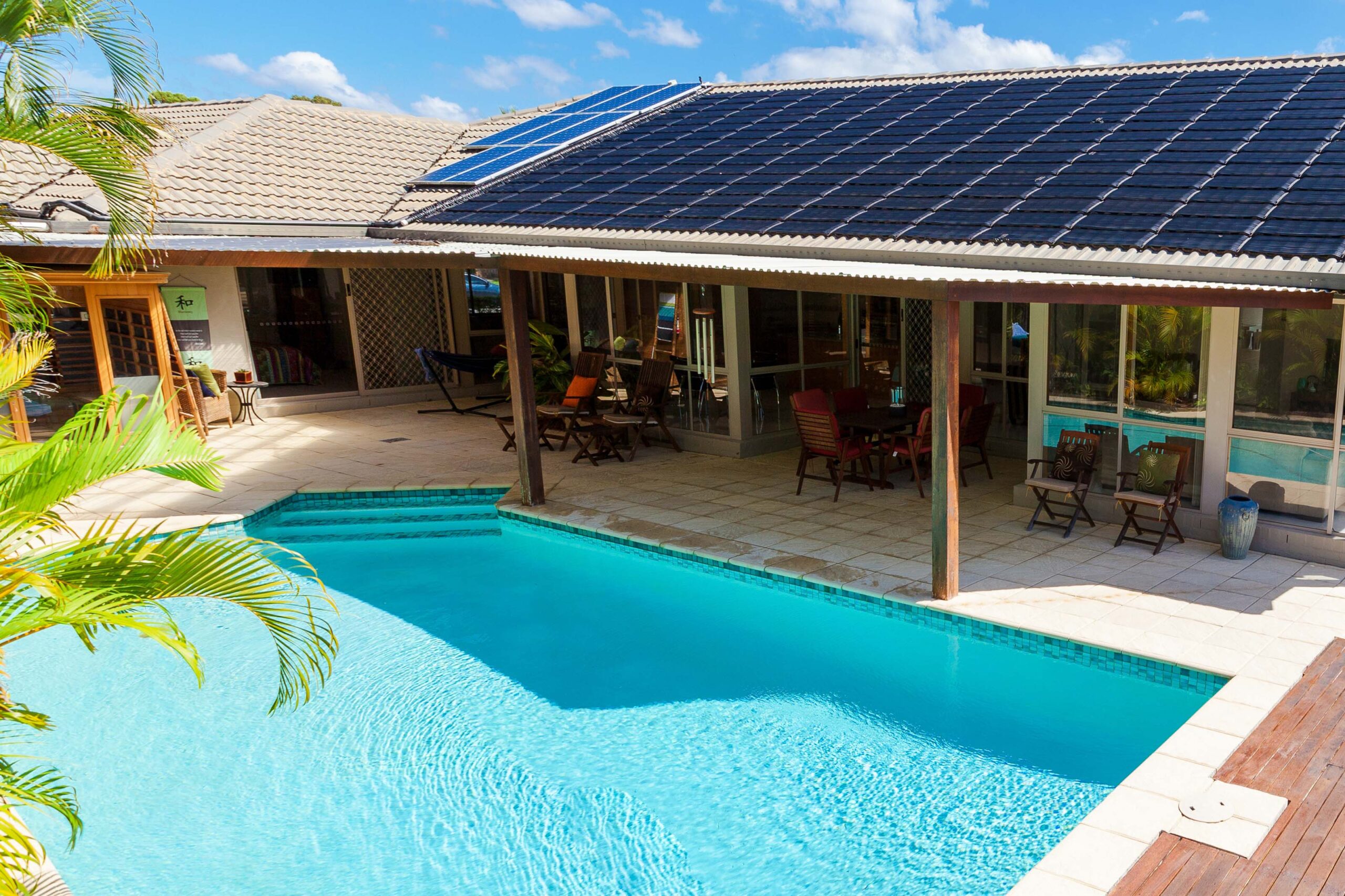 Relaxing poolside at a sunny home with solar panels on the roof