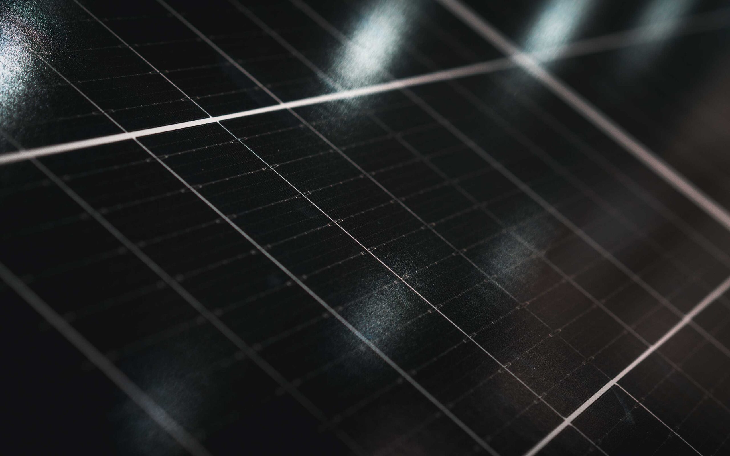 Close-up of a solar panel with grid-patterned photovoltaic cells and glossy surface reflecting light.