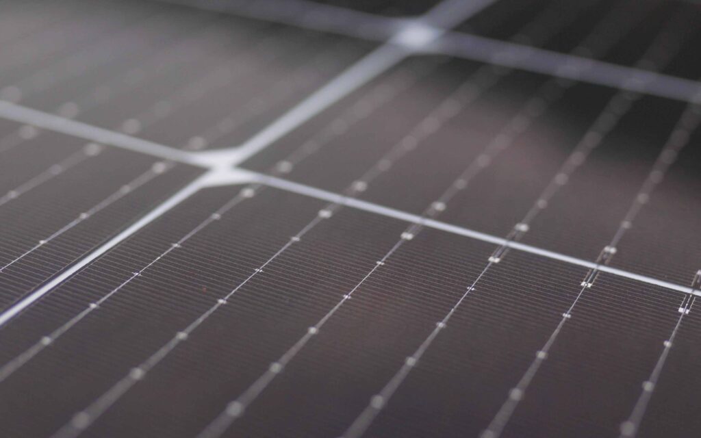 Close-up of a solar panel featuring a grid of dark, reflective photovoltaic cells with fine metallic lines