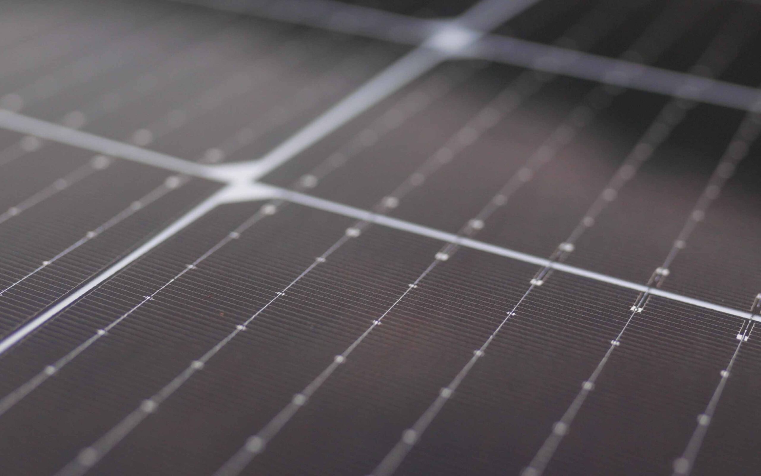 Close-up of a solar panel featuring a grid of dark, reflective photovoltaic cells with fine metallic lines